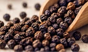 Black peppercorns with a wooden scoop